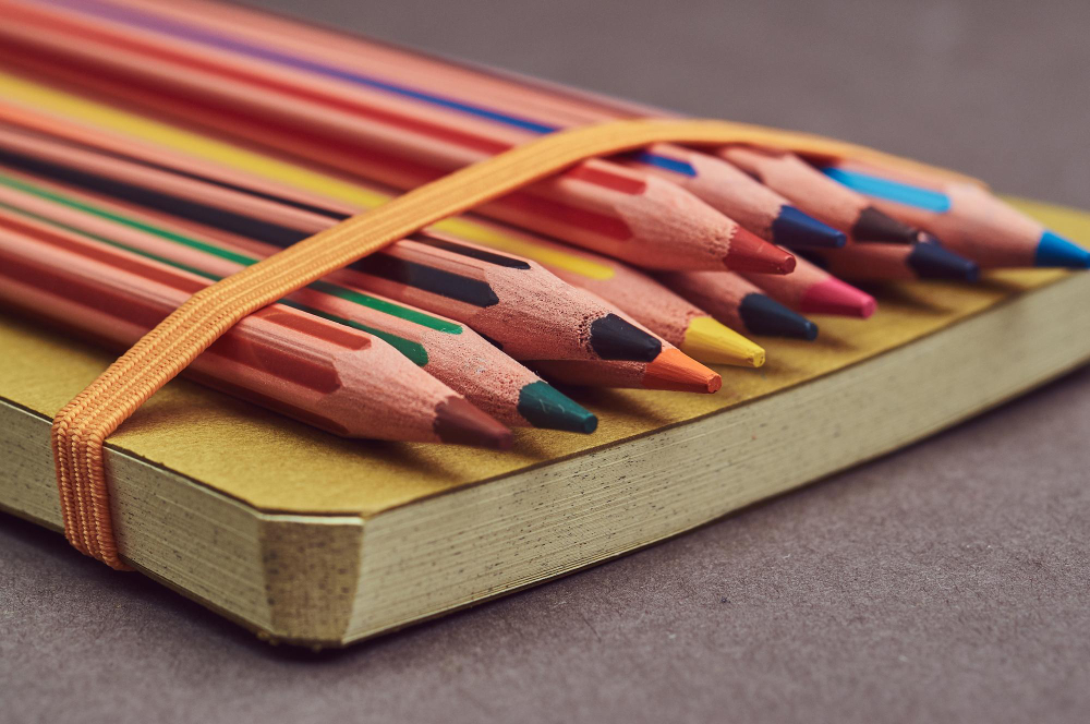 Набір кольорових художніх олівців та скетчбук на столі для малювання