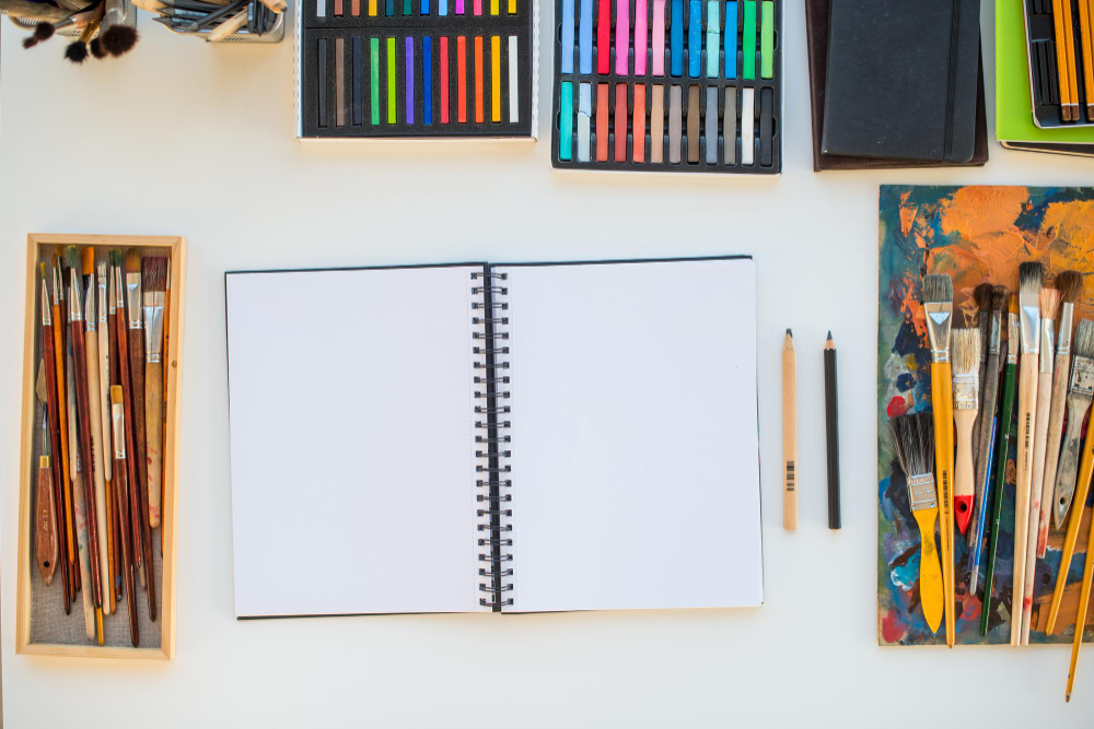 Відкритий скетчбук для малювання з чистими аркушами на робочому столі художника.